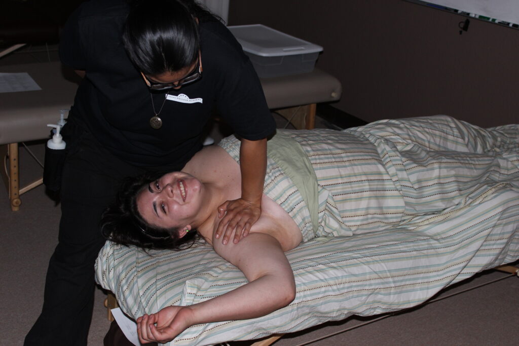 Sarah Suarez receiving a shoulder stretch from a classmate during hands-on massage training at TMA