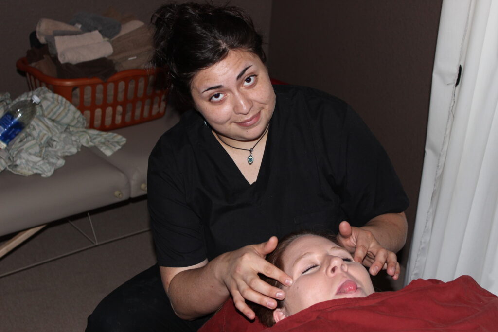 Sarah Suarez performing a facial massage on a classmate during a class session at Texas Massage Academy